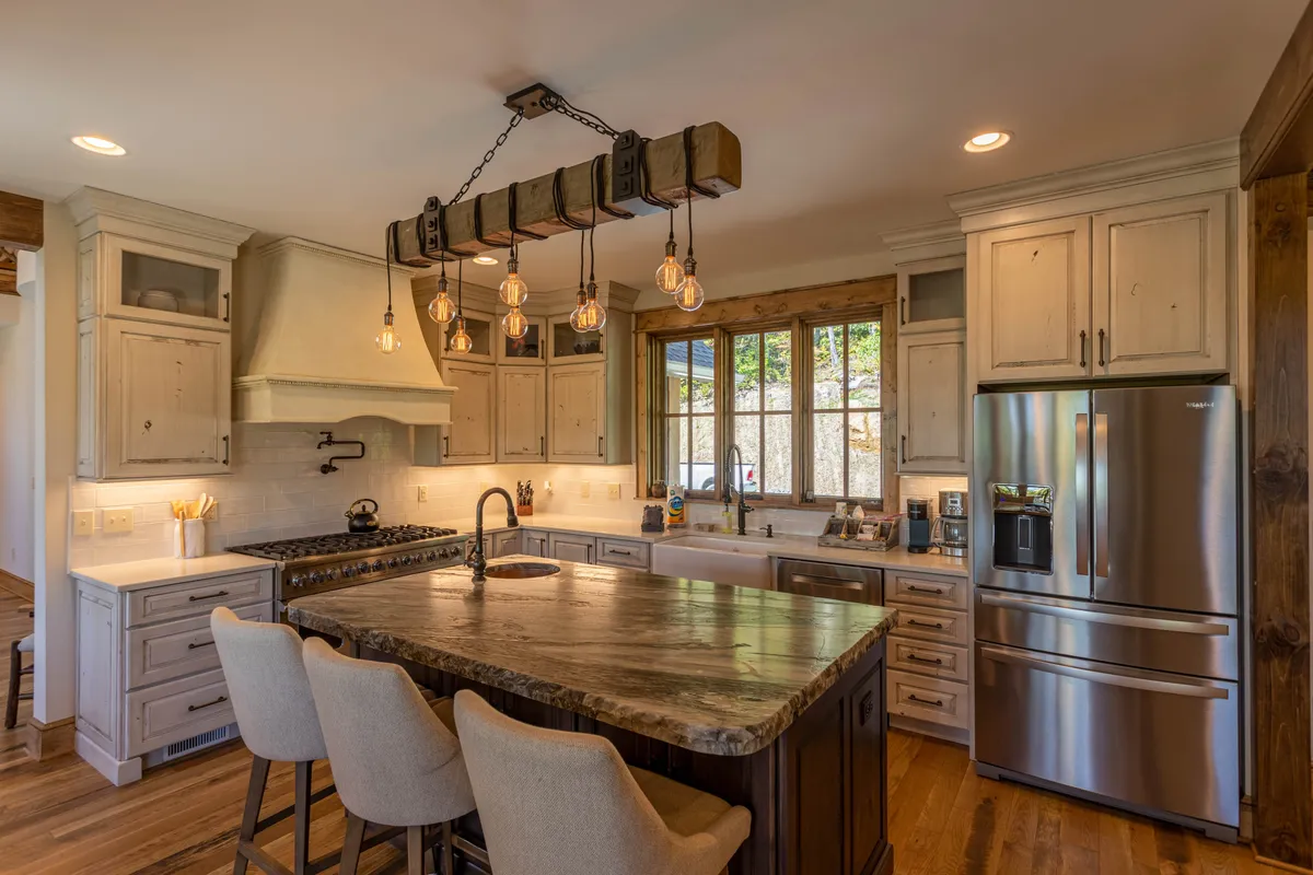A modern chef’s kitchen with a large kitchen island, sleek stainless steel appliances, and a distinctive light fixture. The setup is perfect for preparing meals and hosting interactive culinary experiences.