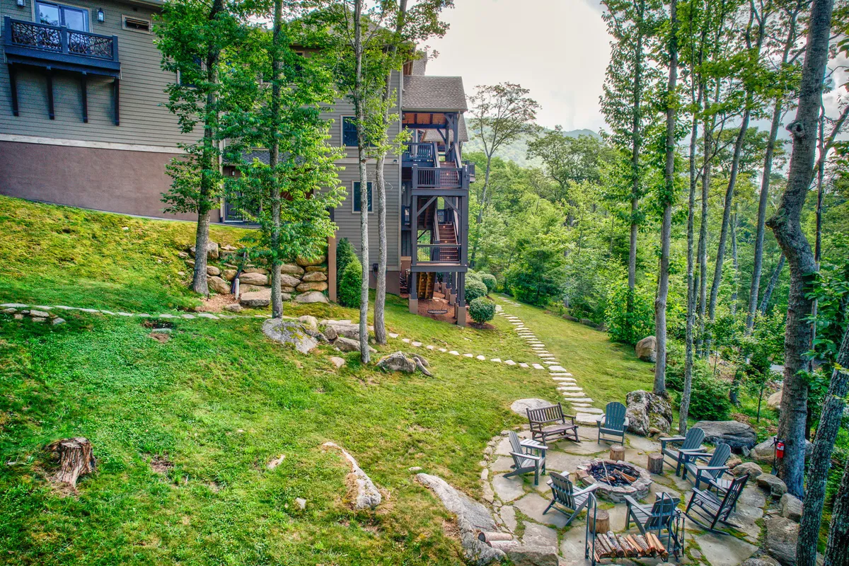 This image captures a communal fire pit surrounded by Adirondack chairs on a stone patio, with a building façade and trees in the background. The relaxed, convivial setting suggests evenings spent gathering outdoors, sharing stories, and enjoying sunsets or stargazing in the mountain air.
