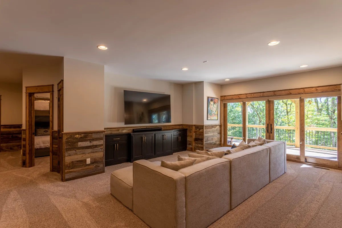 A glimpse inside the living area, featuring a comfortable sofa, a large television, sliding glass doors, and wooden accents. The space is bright and modern, with streaming and entertainment amenities clearly visible.