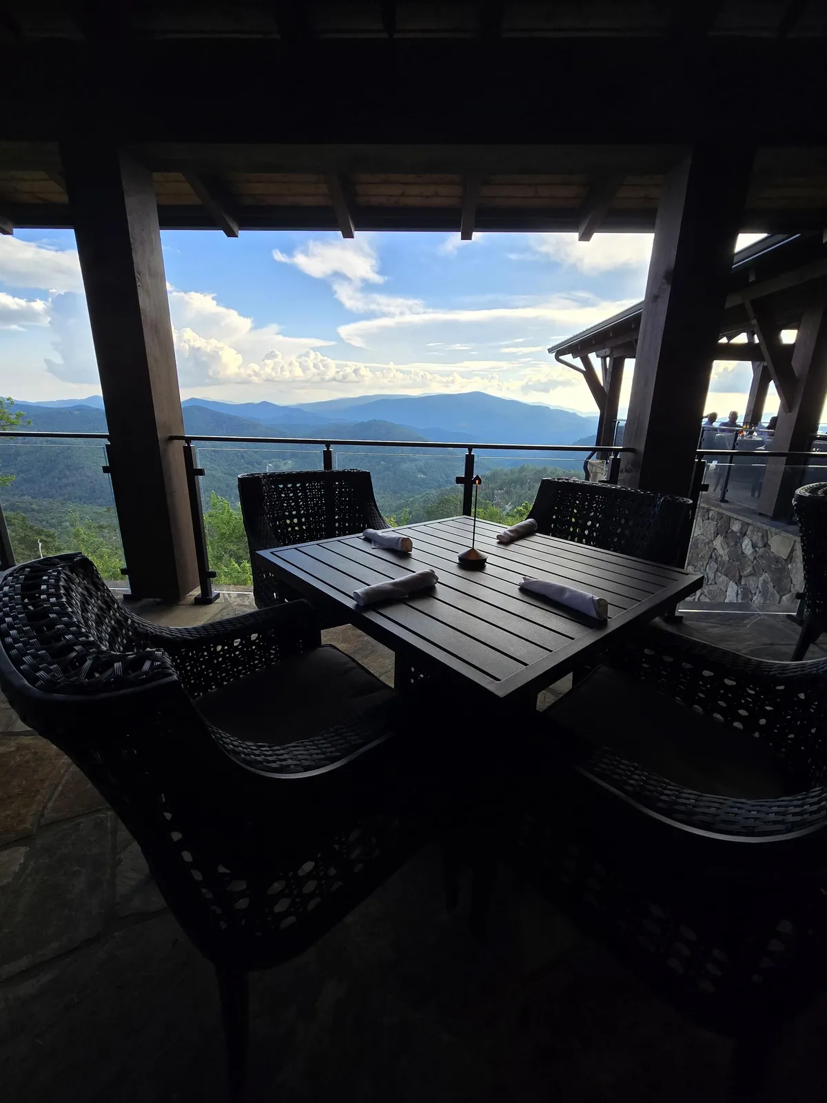An outdoor dining table set against a stunning mountain view, with ample seating and clear skies. The setup is perfect for hosting al fresco meetings, strategy sessions, or after-work celebrations, blending business with the pleasure of the natural surroundings.