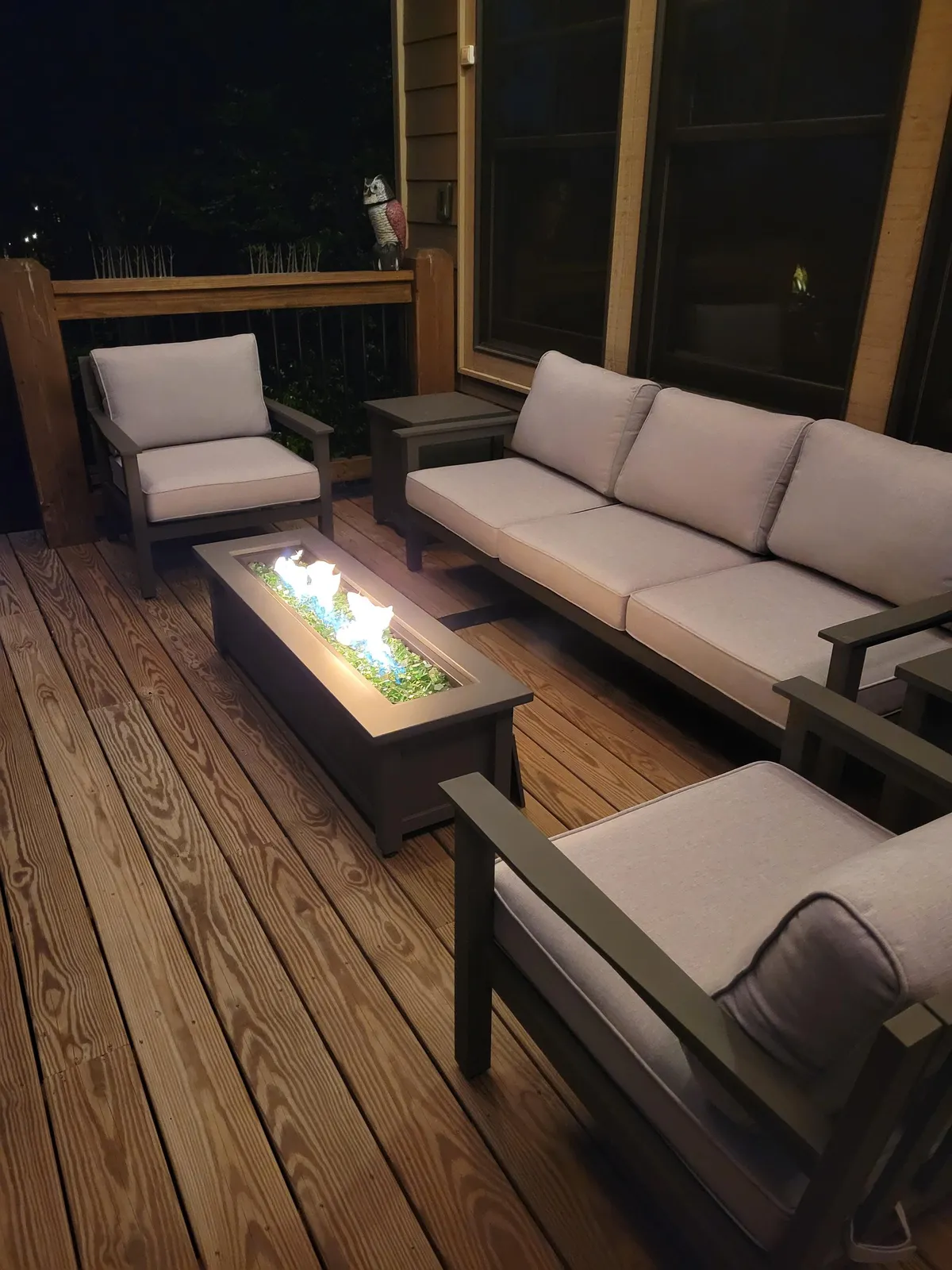 A cozy interior space centered on a modern fire pit, surrounded by comfortable seating and a decorative owl statue. The ambiance is intimate, perfect for gatherings and unwinding by the fire.