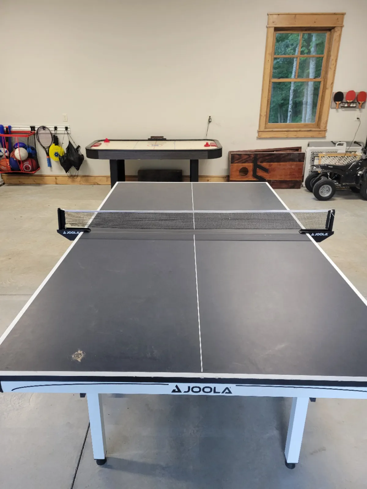 A brightly lit game room with a ping pong table and air hockey table set near a window with a scenic view, creating a spirited atmosphere for family tournaments and friendly rivalries.