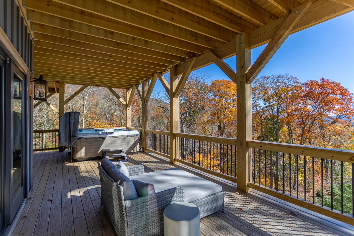 This exterior image features a luxurious hot tub (Bullfrog Spa) nestled on a wooden deck, surrounded by autumn foliage and cozy outdoor seating. The mountain view in the background hints at privacy and tranquility. The setting captures the relaxation and indulgence described in the section, and the outdoor spa experience with nature views is a hallmark of high-end mountain retreats.