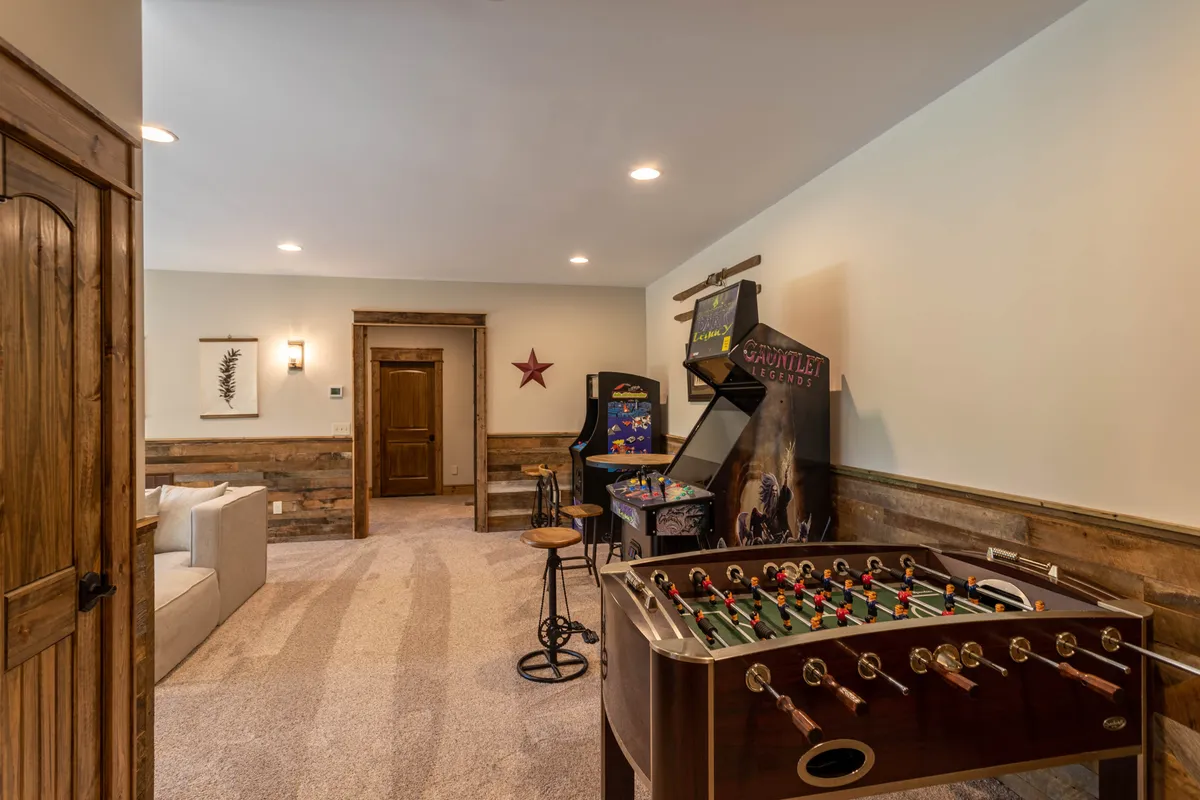 A dynamic view of the entertainment area featuring a foosball table, classic arcade games, and inviting seating. The space exudes excitement and is ideal for energetic matches and nostalgic gaming challenges.