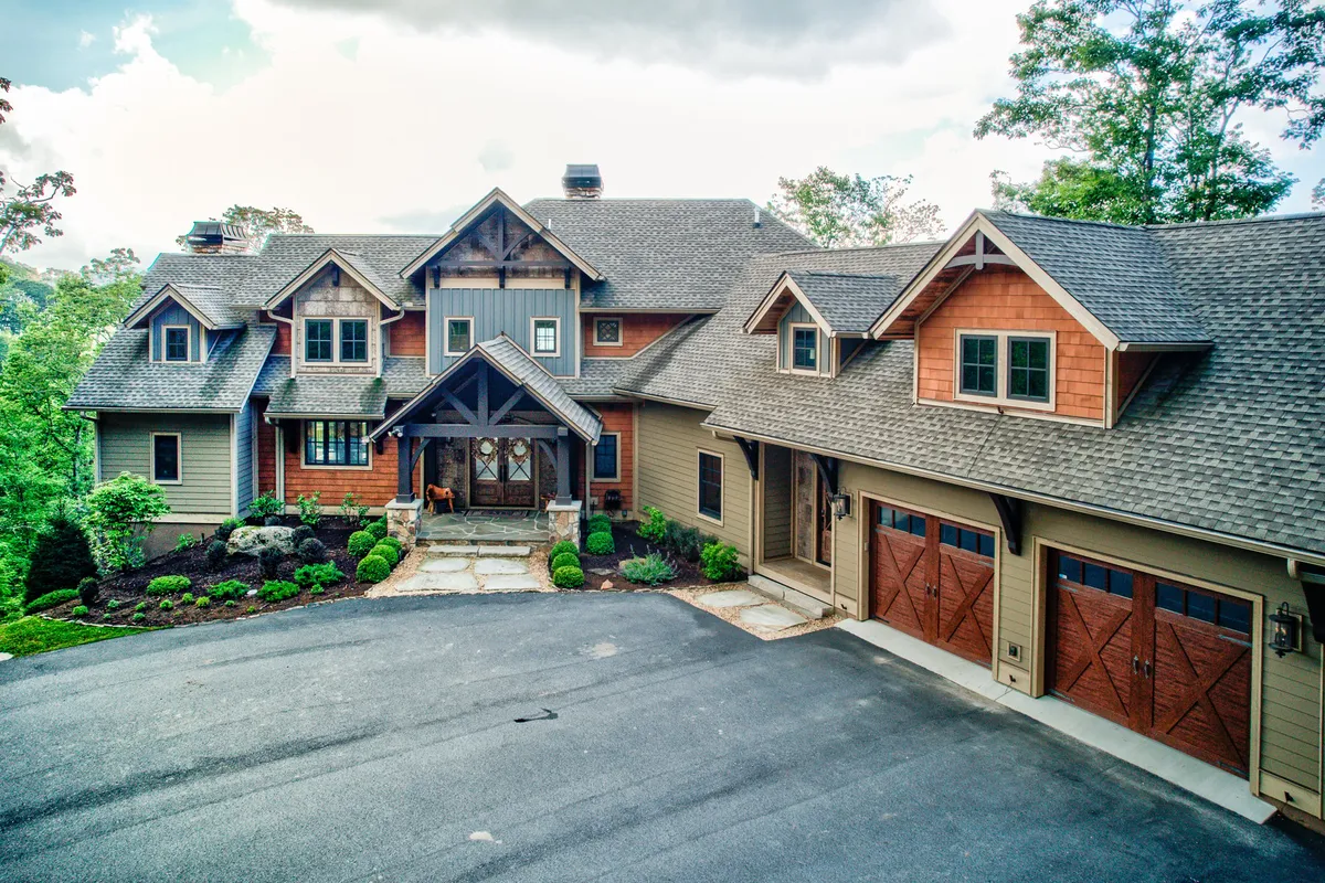 This exterior image highlights the front entrance of the home, featuring a stone pathway, garage doors, and a landscaped garden. The scene is welcoming and reveals the home’s modern amenities and accessibility.